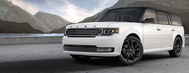 a white ford flex parked on pavement with mountains in the background