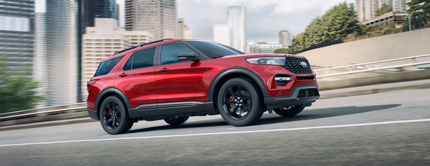 a red ford explorer ST drives on the road in a city 