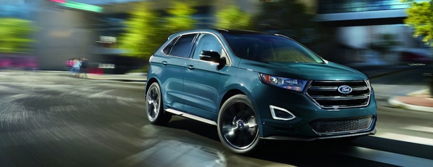 a blue ford edge with a blurry city night background 