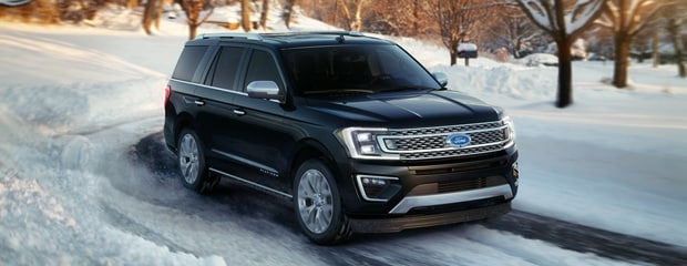 a black ford SUV driving through snow 