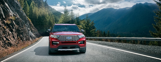 a red ford explorer driving through mountains 